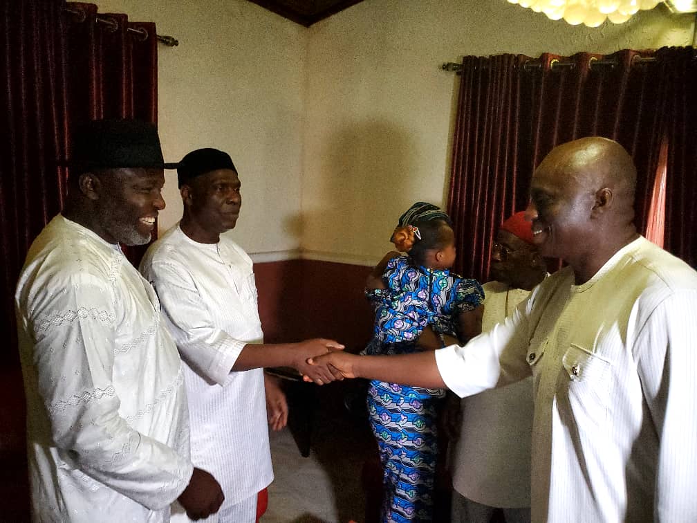 Two men shaking hands while Chief Tony Amechi watches